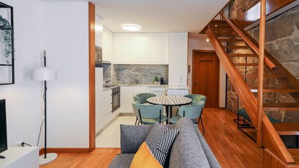 Un espacio habitable compacto con kitchenette, comedor y una escalera.