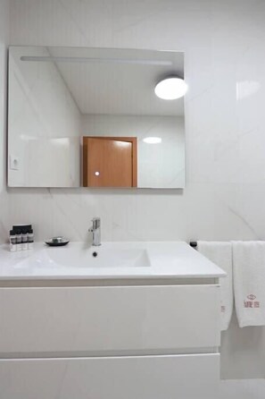A modern bathroom with a white vanity, a mirror, a towel rack, and a small cabinet. - HM - Ribeira Historical Apartment (Porto)