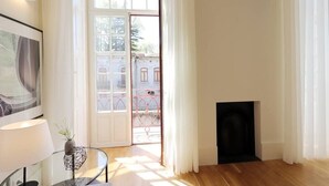 Een kamer met een glazen tafel, een lamp, een open haard en een deur naar een buiten balkon.