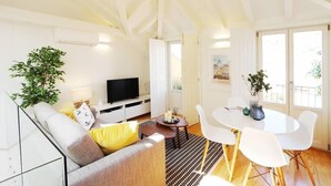 A modern living room with a sofa, TV, dining table, and chairs.