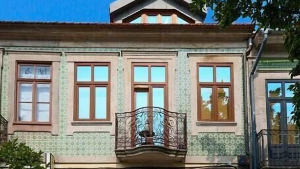 A three-story building with a symmetrical facade, large wooden doors, and a balcony with ornate railings. - HM - Home Feeling Studio Campanhã (Porto)