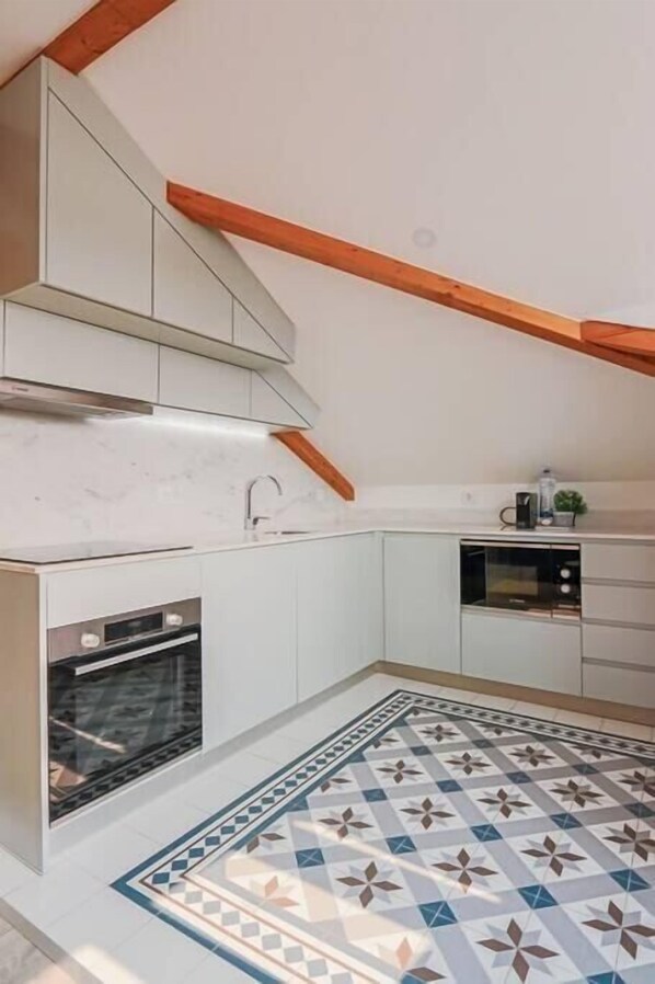 A kitchen with white cabinets, a built-in oven, a microwave, and a coffee maker on the countertop.