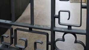 A metal gate with geometric patterns, a narrow alleyway, and buildings in the background. - HM - Carlos Alberto Apartment 2 (Porto)