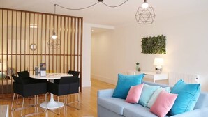 A modern living room with a light blue sofa, black chairs, a wooden partition, and a small table with a lamp. - HM - Carlos Alberto Apartment 2 (Porto)