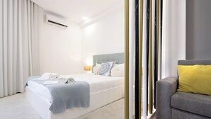 Moderni hotellihuone, jossa on suuri sänky, harmaa sohva ja pieni pöytä.
