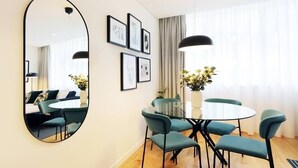 A modern dining area with a round glass table, teal chairs, and a large mirror on the wall. - HM - Sta Catarina Charming Apartment (Porto)