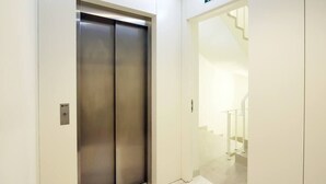 An elevator with a metallic finish and a glass door, leading to a staircase. - HM - Sta Catarina Charming Apartment (Porto)