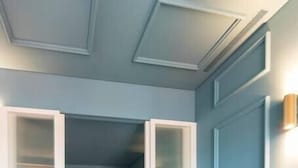 Ein modernes Wohnzimmer mit einer Couch, einem Fernseher, einer Pflanze und einer Schiebetür, die in ein Schlafzimmer führt.