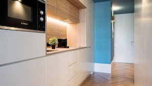 Eine moderne Küche mit weißen Schränken, einer Bosch-Mikrowelle und einer Holzausziehtafel.