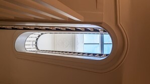 A view through a window with a decorative grille, a ceiling with a wavy design, and a reflection of a window with a geometric pattern. - HM Oporto Studio Pool Oasis (Porto)