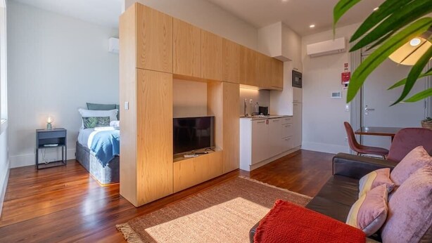 A compact living space with a kitchenette, a bed, a TV, and a seating area. - HM Oporto Studio Pool Oasis (Porto)