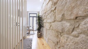 A narrow hallway with a wooden floor, a stone wall, and a potted plant. - HM - Pinheiro Downtown Living (Porto)