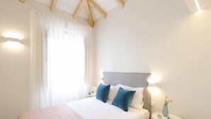 A neatly arranged bedroom with a bed, bedside tables, and a nightstand.