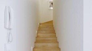 A wooden staircase in a hallway with white walls.