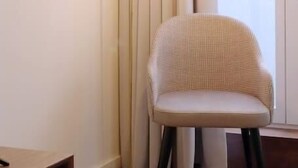 Una habitación moderna con una lámpara de pie, una silla y un cuadro en la pared.