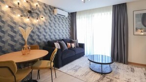 Un salon moderne avec un canapé, une table basse ronde et un coin repas avec des chaises.