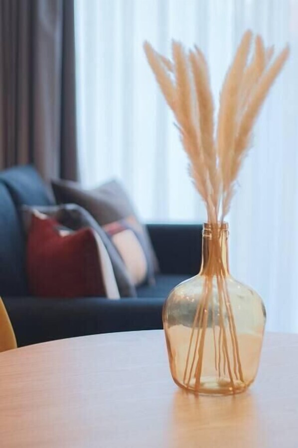 A clear glass vase with dried pampas grass on a wooden table.