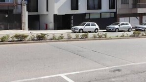 Un immeuble résidentiel moderne à plusieurs étages, doté d’une façade symétrique, de grandes fenêtres et d’un espace de stationnement où sont garées plusieurs voitures.