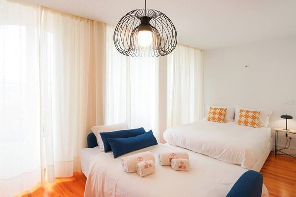 Une chambre d’hôtel avec deux lits, un luminaire suspendu et une table de chevet avec une lampe.