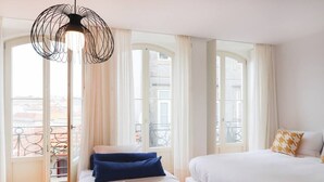 A hotel room with a bed, a window with curtains, a balcony, and a hanging light fixture. - HM – Historic Downtown Batalha Studio (Porto)