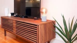 A wooden entertainment unit with a flat-screen TV, a lamp, and a potted plant. - HM – Historic Downtown Batalha Studio (Porto)