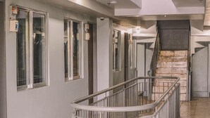 Ein Flur mit Metallgeländer, einer Treppe und einer Tür mit Überwachungskamera.