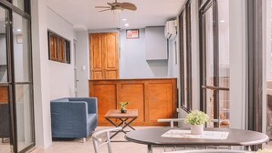 Ein modernes Interieur mit einem runden Esstisch, einem blauen Sofa, Holzschränken und großen Fenstern.