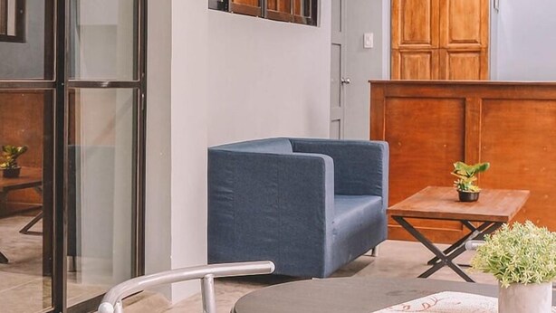 Ein modernes Zimmer mit einem blauen Sofa, einem kleinen Tisch mit einer Pflanze und einer Glastrennwand.