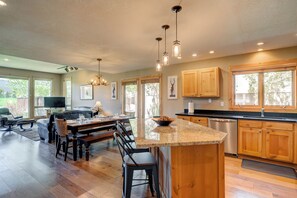 A spacious kitchen with wooden cabinets, a granite countertop, and a dining area with a table and chairs.