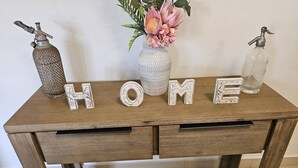 A wooden desk with the word "HOME" spelled out in decorative letters, flanked by two vintage-style bottles. - Yiayi's House Getaway (Wagaman)