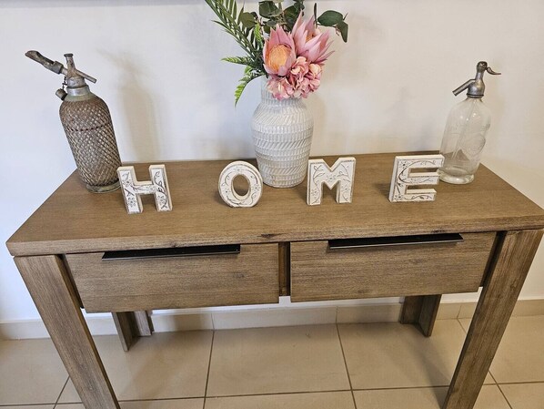 A wooden desk with the word "HOME" spelled out in decorative letters, flanked by two vintage-style bottles. - Yiayi's House Getaway (Wagaman)