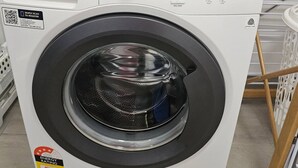 A front-loading washing machine with a control panel, a QR code, and a water efficiency rating sticker. - Yiayi's House Getaway (Wagaman)