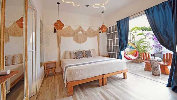 A bedroom with a wooden bed, a large mirror, and a view of the outdoors. - Casa Nomis Cancun (Cancun)