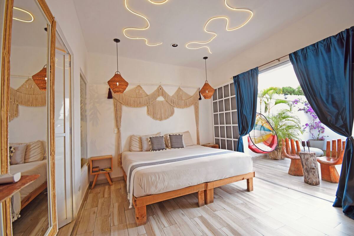 A bedroom with a wooden bed, a large mirror, and a view of the outdoors.