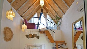 A bedroom with a bed, a hanging light fixture, a wooden staircase, and a mirror. - Casa Nomis Cancun (Cancun)