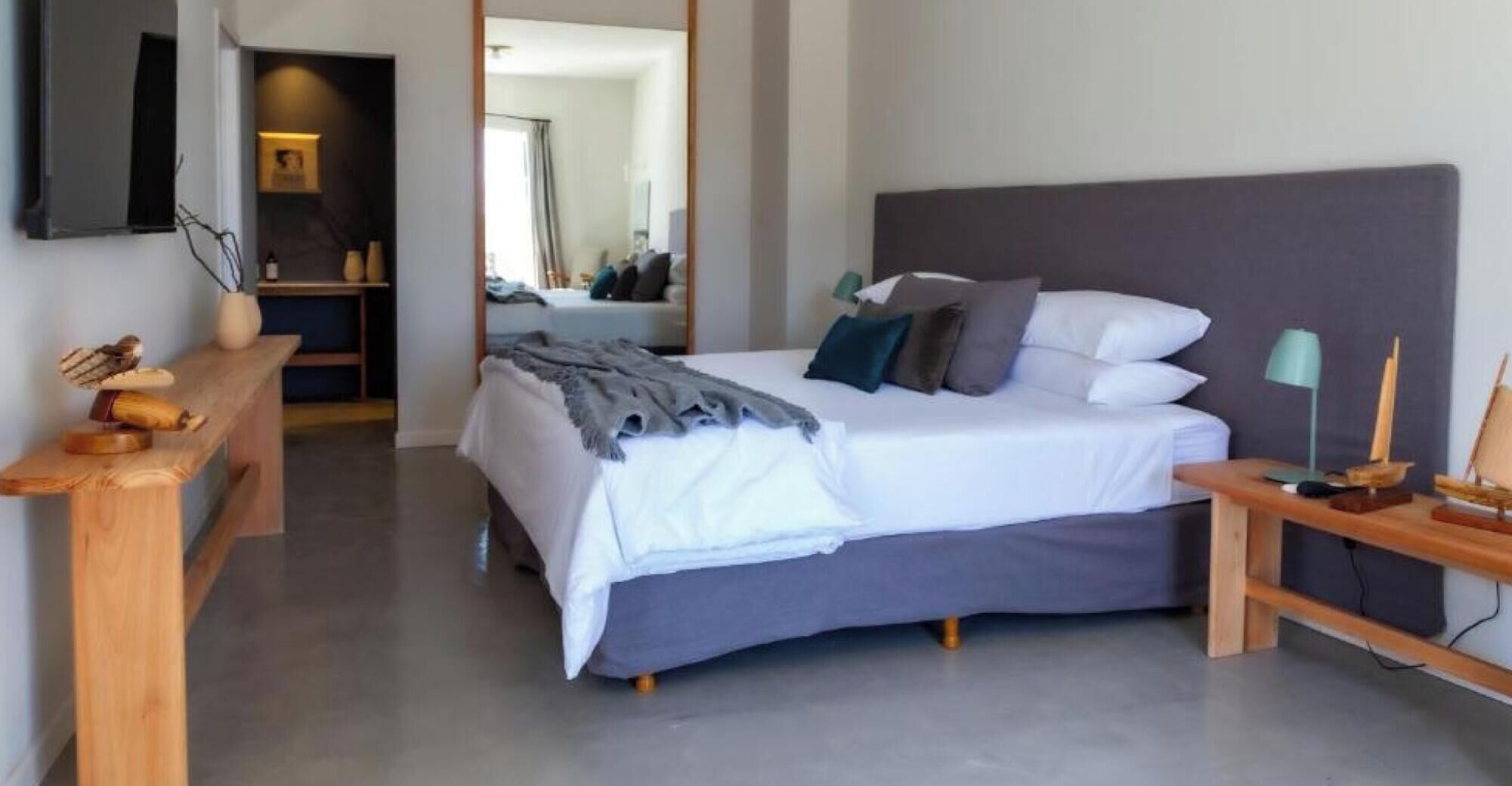 Une chambre à coucher moderne avec un lit, des tables de chevet, un bureau et un miroir.
