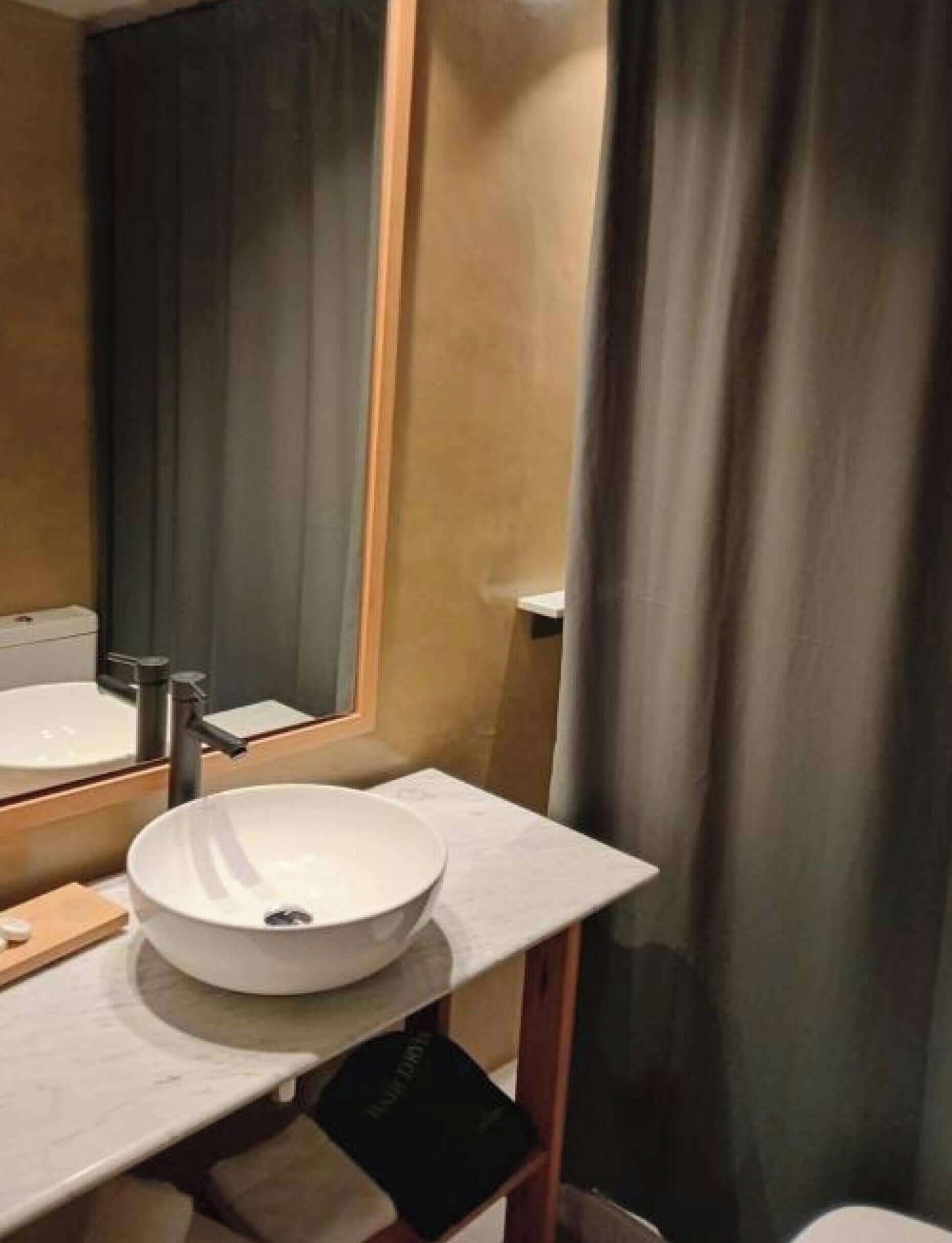 A bathroom with a white sink, mirror, and wooden vanity.