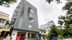 Un bâtiment moderne doté d’une façade géométrique originale, d’une entrée rouge et d’un escalier apparent menant à un étage supérieur.