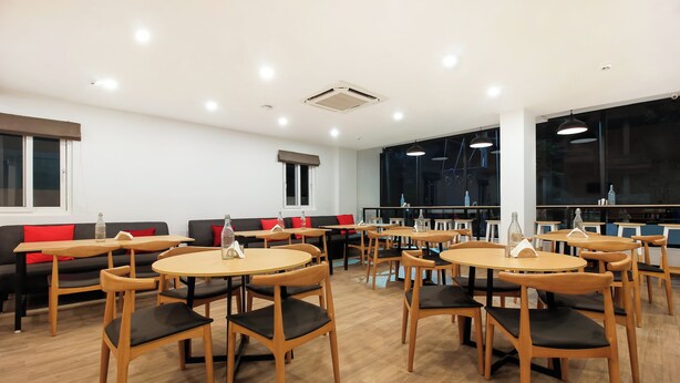 Un espace repas moderne avec des tables et des chaises rondes, un canapé et de grandes fenêtres.