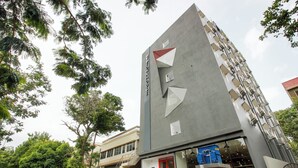 Un bâtiment moderne avec une porte rouge et un escalier menant à l’entrée.