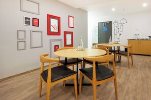 Ein moderner Essbereich mit runden Tischen und Stühlen, gerahmten Kunstwerken an den Wänden und einem minimalistischen Design.