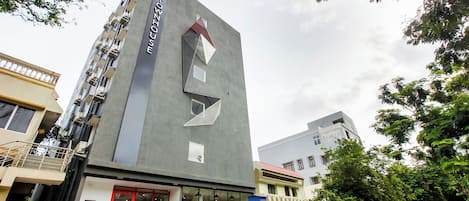 Um edifício moderno com fachada geométrica marcante, entrada vermelha e escadaria visível que leva a um andar superior.