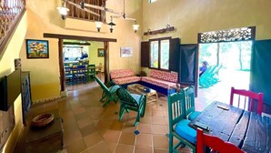 Amplia sala de estar con techo alto, escalera de madera y balcón con vista a un jardín.