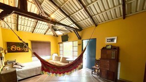 Una habitación amplia con una hamaca, una cama, un escritorio y una silla.