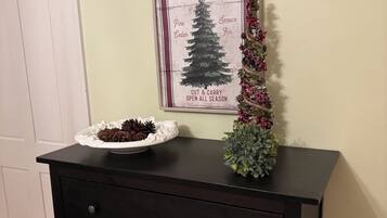 Un aparador de madera oscura con un letrero enmarcado encima, una pequeña planta en maceta y un plato decorativo con piñas.