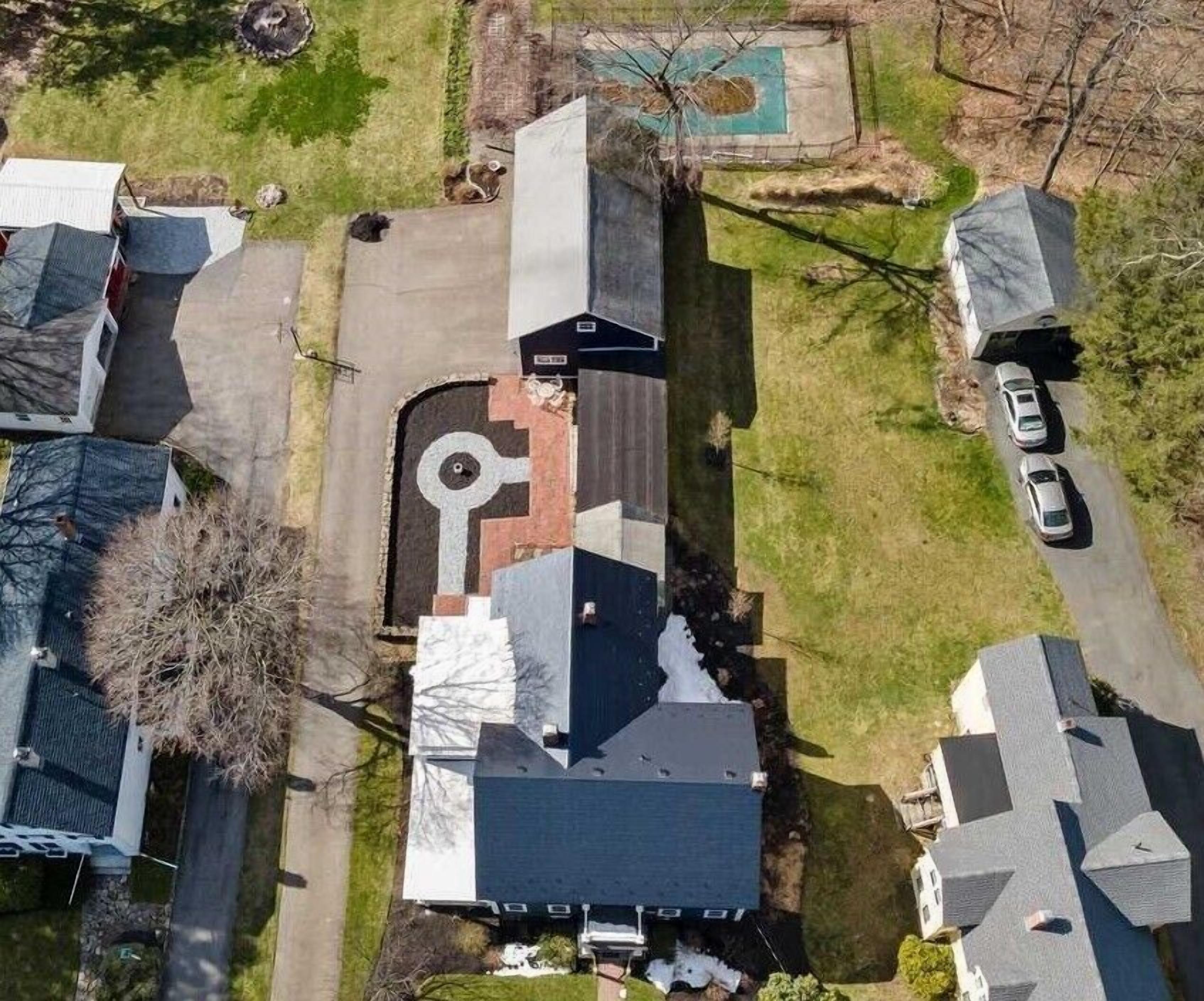 An aerial view of a residential area with houses, a driveway, and a swimming pool.