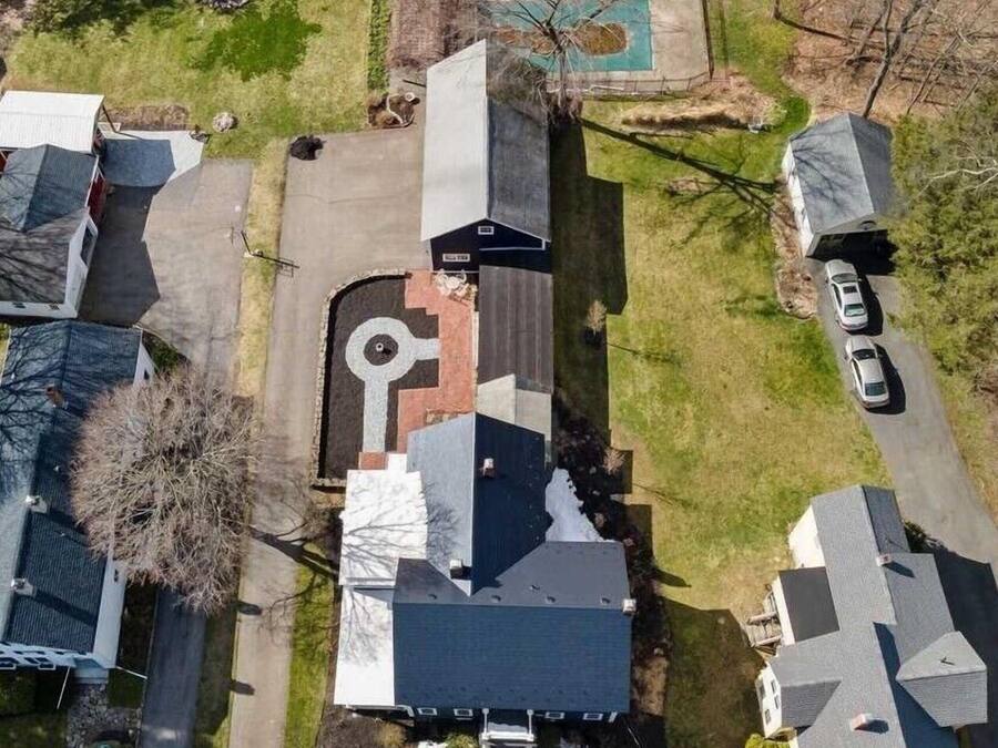 An aerial view of a residential area with houses, a driveway, and a swimming pool.