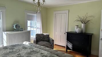 A bedroom with a bed, a chair, a dresser, and a window with curtains.