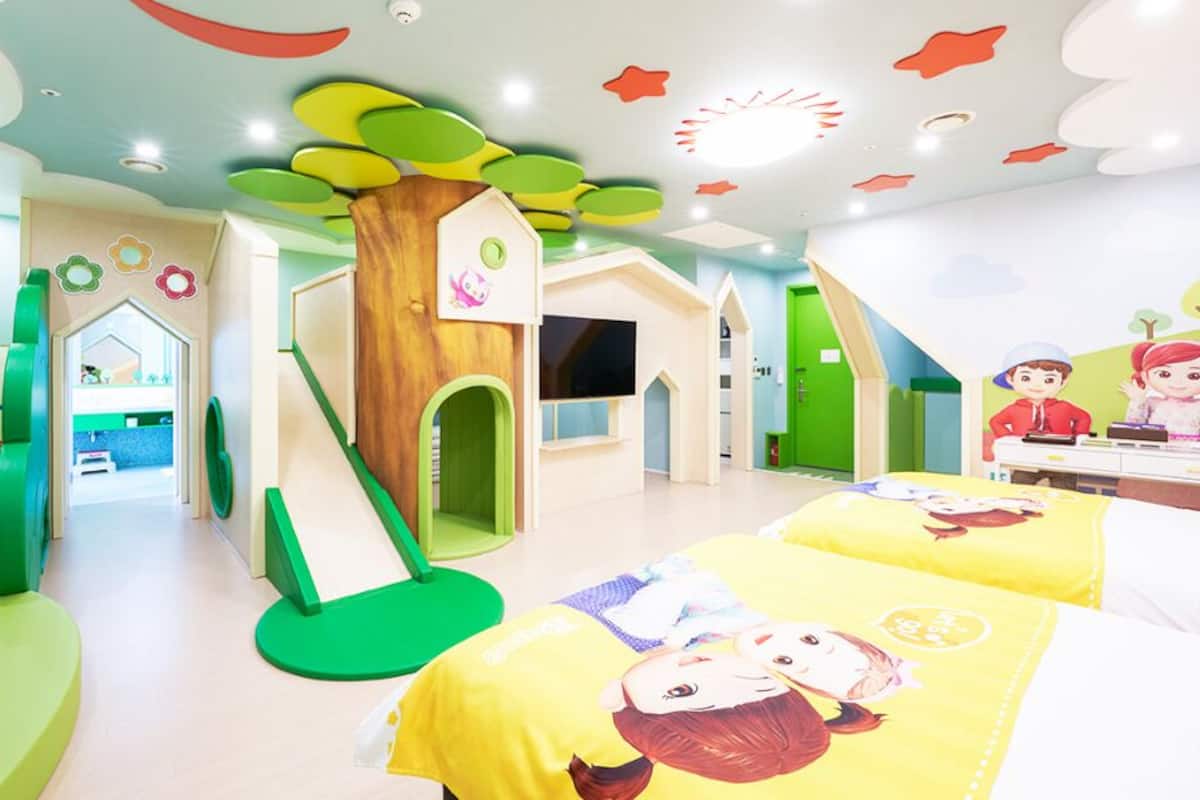 Una sala de juegos para niños con un tobogán, estructuras de juego y ropa de cama temática.