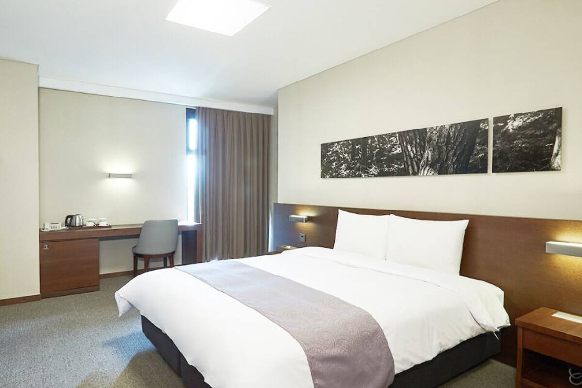 Una habitación de hotel con una cama grande, un escritorio, una silla y un televisor.